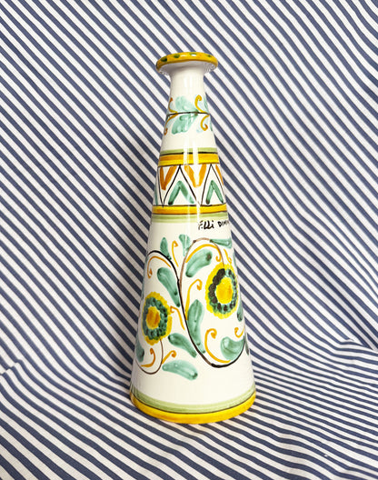 Hand-painted Sicilian ceramic bottle with blue flower patterns in front of a striped background