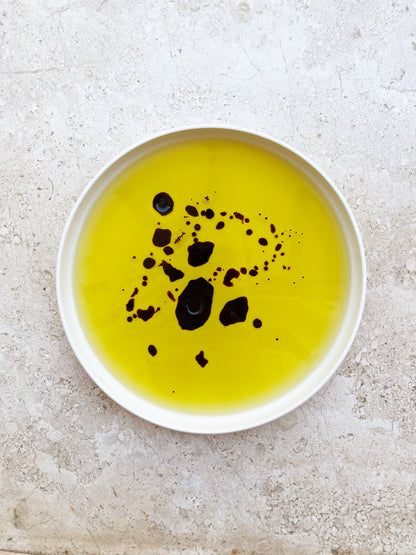 White dish with oro sicani sicilian extra virgin olive oil and balsamic vinegar on travertine marble tabletop