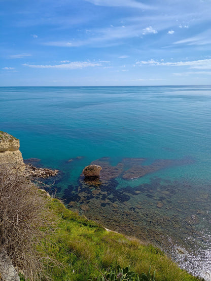 Coastal scene of Sciacca, Sicily, with clear blue water and sky, rocks in the foreground